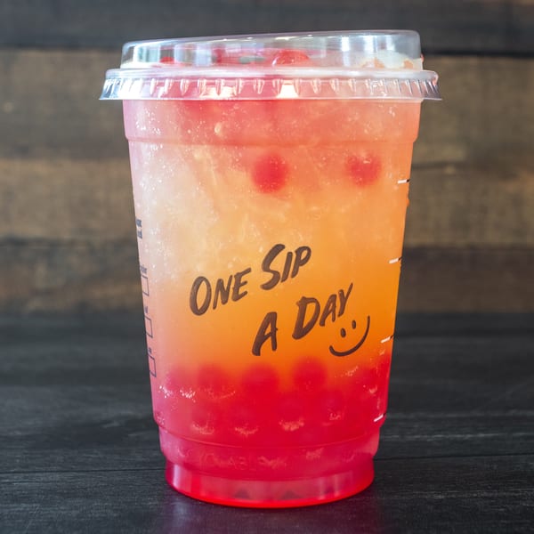 Clear cup with layered red and orange drink, boba, and 'One Sip A Day' text.